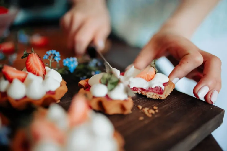 A hand cutting a floral and berry tart dessert